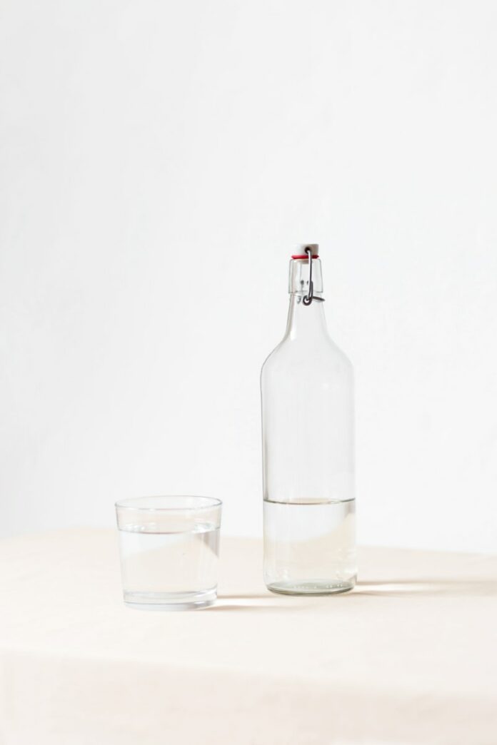 Photo by Laura Mitulla rocks glass beside half empty bottle on white surface
