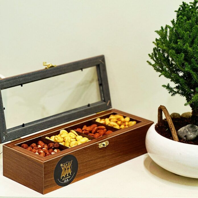 Photo by Aryo Garshasbi a wooden box filled with nuts next to a potted tree