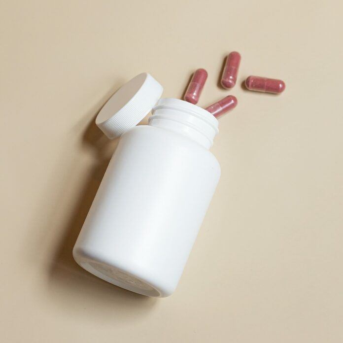 Photo by Supliful - Supplements On Demand a white bottle with red and white pills