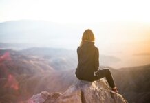 심리적 안정을 위한 운동의 역할 person sitting on top of gray rock overlooking mountain during daytime