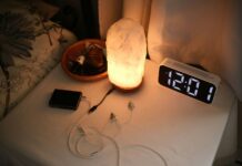슬립테크로 재정비되는 우리의 밤, 수면 건강 관리 트렌드 뜬다 Nightstand with a lamp, clock, and chargers.
